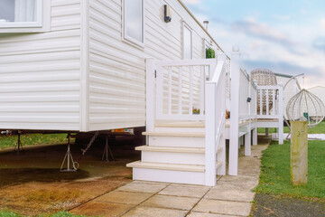 Obraz premium Cozy mobile home with a deck and staircase at a peaceful park atmosphere during a cloudy afternoon