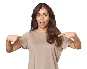 Middle Eastern woman in studio surprised pointing with finger, smiling broadly.