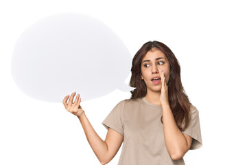 Middle Eastern woman holding comic bubble is saying a secret hot braking news and looking aside