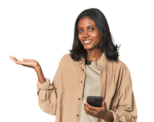 Young Indian woman using a smartphone showing a copy space on a palm and holding another hand on waist.