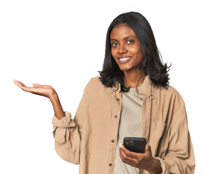 Young Indian woman using a smartphone showing a copy space on a palm and holding another hand on waist.