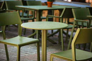 Empty plastic chairs and tables in a street cafe early morning, table for two close-up.
