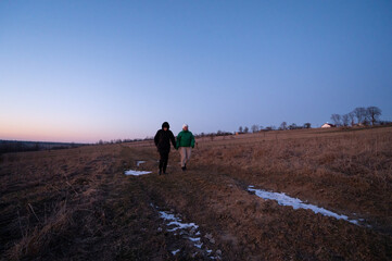 Couples stroll across a serene meadow at dusk, hand in hand, as the soft glow of twilight embraces...