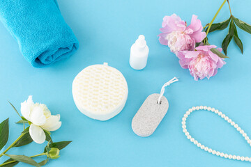Towel with body care products and peony flowers on the blue background.