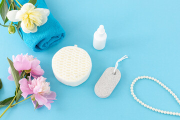 Towel with body care products and peony flowers on the blue background.