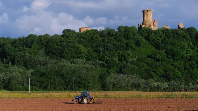 A tractor plowing a field under the ruins of the ancient tower of Velia (Elea) in Ascea