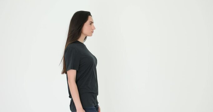 Woman model with long brunette hair maintains tall posture and elegant steps on catwalk. Female rehearses model walk with concentration. Slow motion
