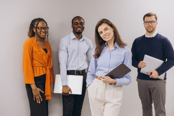Group of diverse business professionals standing confidently with digital devices, showcasing...