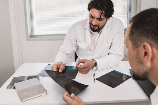 Doctor surgeon traumatologist looks at an X-ray with male petient. fracture, arthrosis, arthritis, joint deformation, dysplasia, meniscus injury. orthopedist specialist consultation