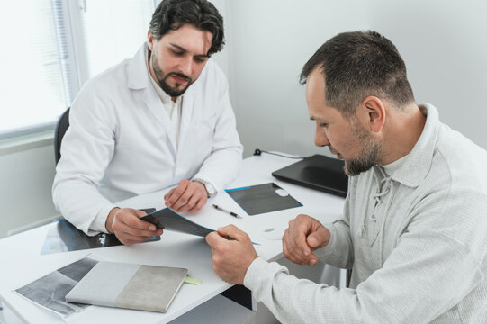 Doctor surgeon traumatologist looks at an X-ray with male petient. fracture, arthrosis, arthritis, joint deformation, dysplasia, meniscus injury. orthopedist specialist consultation