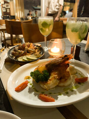 Gourmet Shrimp Dish and Cocktails at Candlelit Restaurant Table
