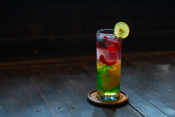 Refreshing iced nutmeg juice or pala juice with colorful jelly and syrup in highball glass, on wood surface, with shallow depth of field