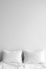 Two white pillows on a bed against a white wall in a minimalist style close up studio shot for sleeping and comfort