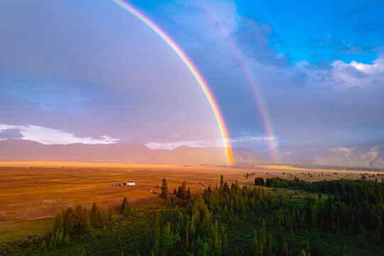 Stunning double rainbow over serene countryside landscape at sunset