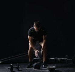 Man clapping hands with talcum powder before training with kettlebell on black background