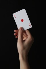 Obraz premium Woman with playing card against black background, closeup