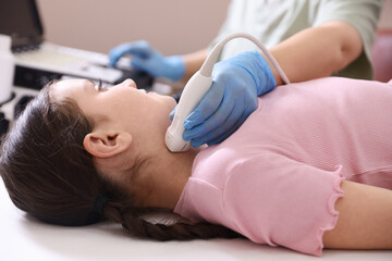 Sonographer conducting girl's thyroid gland ultrasound examination in clinic, closeup