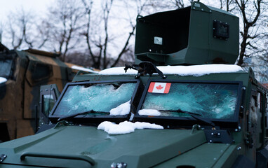 Frozen military vehicle displays Canadian flag during winter in urban area