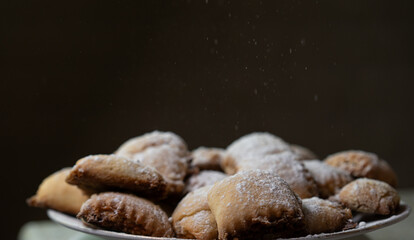 Delicious homemade pastries sprinkled with powdered sugar on a white plate in a cozy kitchen setting