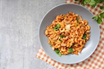 Stir fried macaroni with tomato sauce ,minced pork and egg wi in a grey plate
