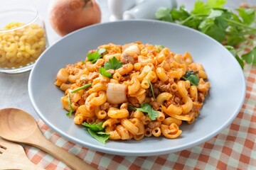 Stir fried macaroni with tomato sauce ,minced pork and egg wi in a grey plate