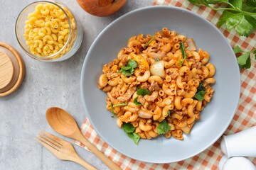 Stir fried macaroni with tomato sauce ,minced pork and egg wi in a grey plate