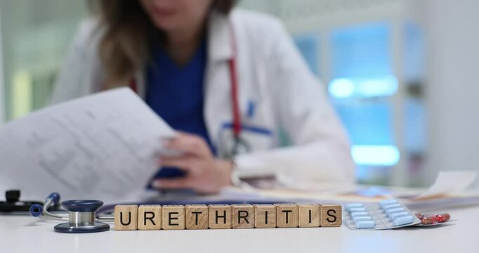 Woman reviews papers near cubes with word Urethritis. Clinical examination and documentation of urethritis condition involving inflammation of urethra