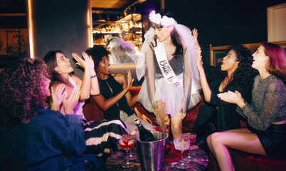 Bride-to-be celebrating with friends a fun evening bachelorette party with drinks