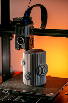 Intricately bizarre 3D-printed vase emerges from the machine glow, evoking Pi Day symmetry and World Creativity Week celebrations, 3D printer, 3D printing