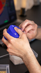 Intricate blue gear twirls in European male's hands, embodying Machine Day's steampunk artistry, innovation Festival; 3D printer, 3D printing