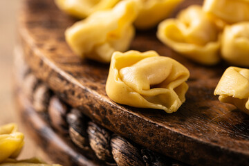 Close up with freshly made tortellini Cappelletti pasta with prosciutto, elegantly arranged on a rustic wooden board with copy space