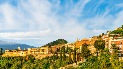 Obraz premium scenic green view of beautiful old yellow mountain towh with vintage church hotel and monastery and amazing high mountain with blue cloudy sky on background
