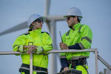 Maintenance engineer team standing at windmills at wind turbine farm. Group of people wear safety...