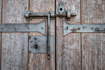 Porta de madeira envelhecida com trinco antigo de metal, um símbolo de durabilidade e história