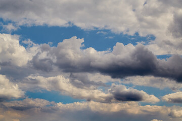 Cumulus clouds in the sky and sunlight on the clouds, cloudy background, clouds before a change in weather, light and dark edges of clouds in the sky.