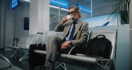 International Airport Terminal: Mature Businessman Sitting in Departure Lounge, Looking at...