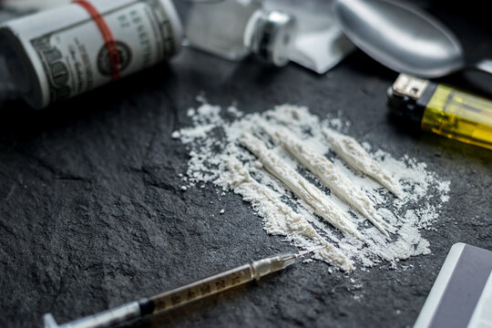 drugs addict problem concept. close up of cocaine powder or heroin, syringe, spoon, lighter for drug paraphernalia and dollar bill from illegal drug dealing, social issues