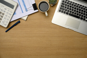Modern office desk with laptop, calculator, coffee, and financial documents
