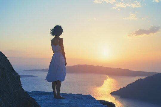 Silhouette of a woman in a white dress gazing at a breathtaking sunset over a serene ocean.