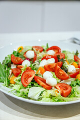 Colorful salad with mixed greens, cherry tomatoes, and mozzarella balls, emphasizing freshness and healthy lifestyle choices