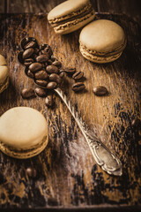 Macarons displayed on a wooden board alongside coffee beans and a vintage spoon, showcasing a delightful dessert arrangement perfect for culinary inspiration