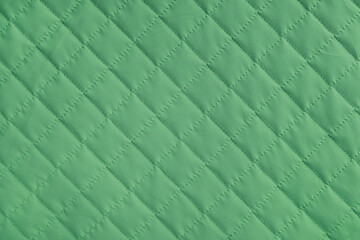 Checkered, diamond stitching pattern, green quilted fabric background. Blanket or puffer jacket,...