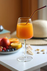 Glass of cocktail, straw hat, sunglasses, books, fresh fruit, chocolate and accessories. Summer essentials on the table. Selective focus.
