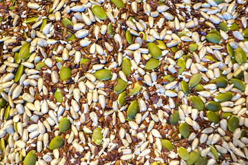 Assorted seeds including pumpkin, sunflower, and flax are scattered on a textured surface, showcasing natural colors and diverse shapes for healthy eating