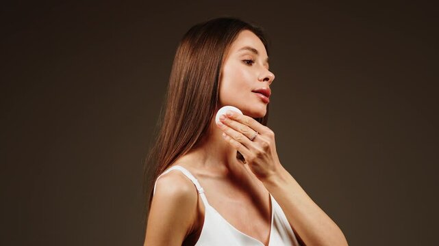 Woman applying makeup with cotton pad in close-up demonstration