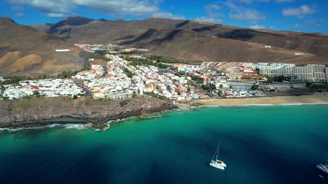 Aerial 4K View of Catamarans Anchored near Morro Jable Beach in Fuerteventura &mdash; Turquoise Coastline, Luxury Sailing and Tourist Town Panorama in Canary Islands