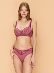 Fototapeta premium Girl model in underwear posing in studio on beige background.