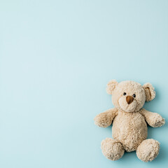 Obraz premium A soft, beige teddy bear with a friendly expression, sitting on a light blue background. The bear has round ears and a cute nose, making it a perfect companion for children.