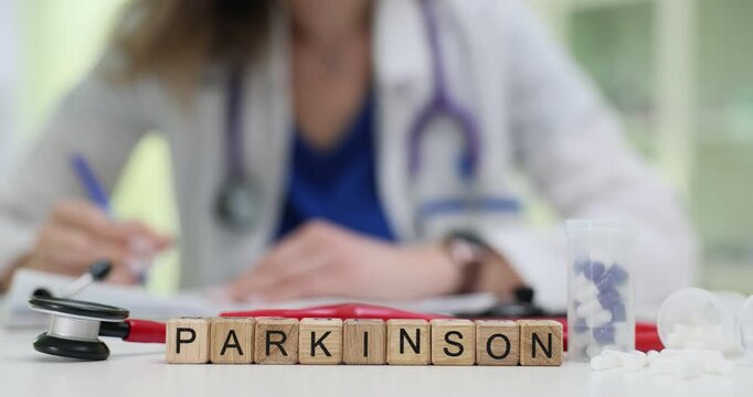 Text Parkinson of wood cubes with stethoscope and pills on doctor table. Medic writes diagnosis managing neurodegenerative disorder treatment