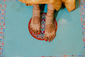 Feet adorned with henna designs on a colorful surface. Intricate patterns and vibrant colors...